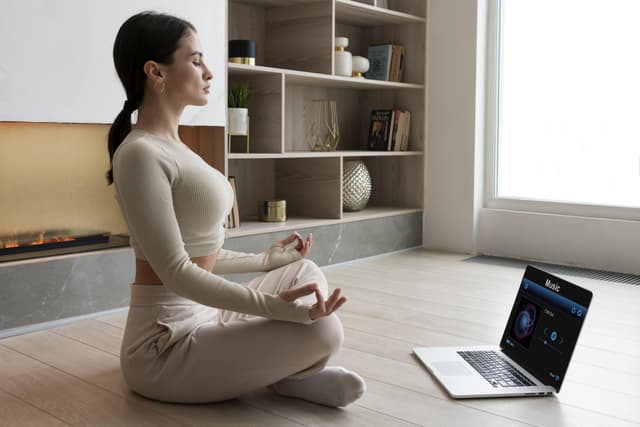 woman meditating home with laptop